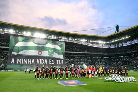 Players line up on the pitch as a tifo is displayed by Sporting Clube de Portugal fans.
