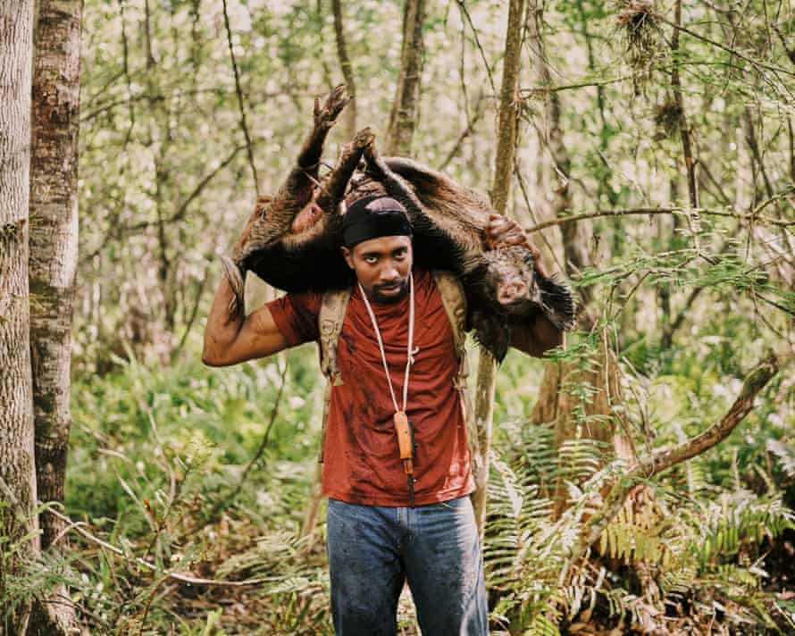 Pompi Rodriguez carries a captured hog out of the marsh.