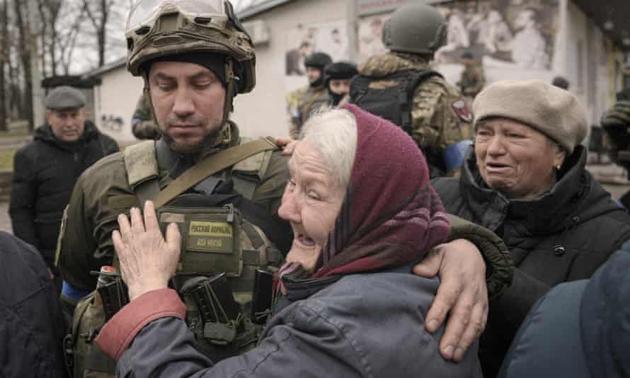 A woman hugs a Ukrainian serviceman after a convoy of military and aid vehicles arrived in the formerly Russian-occupied Kyiv suburb of Bucha