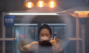 A health worker (rear) collects swabs from a citizen for coronavirus testing at a makeshift clinic outside the Seoul city hall in Seoul, South Korea, 5 January 2021.