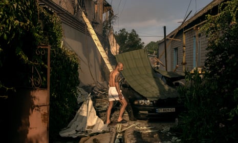 A man walks next to a residential house that was hit during Russian shelling near a flooded area in Kherson, Ukraine.