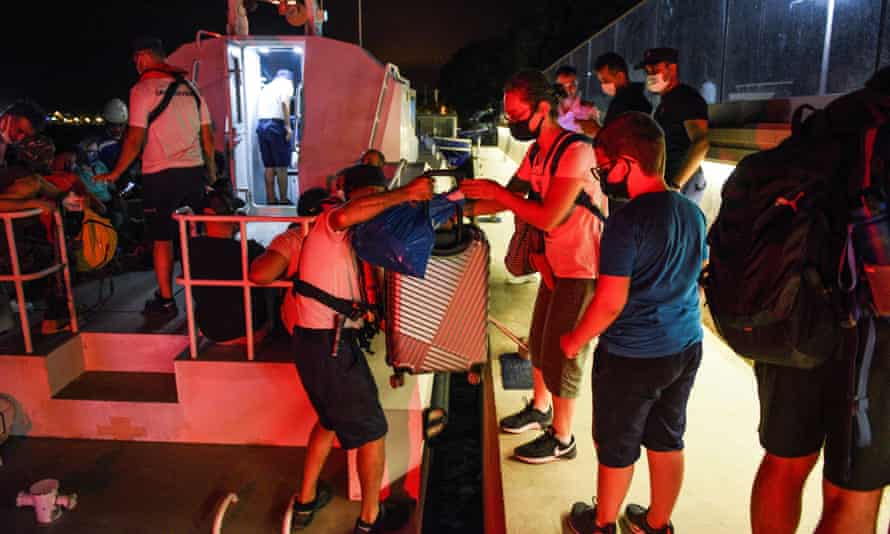 People board a coastguard boat to evacuate the area after fire spread into a coal-fired power plant in Ören.