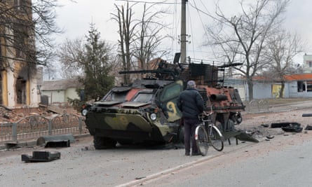 A man looks at a destroyed Ukrainian armoured personnel carrier in Kharkiv.