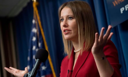 Ksenia Sobchak wearing a red suit speaks into a microphone