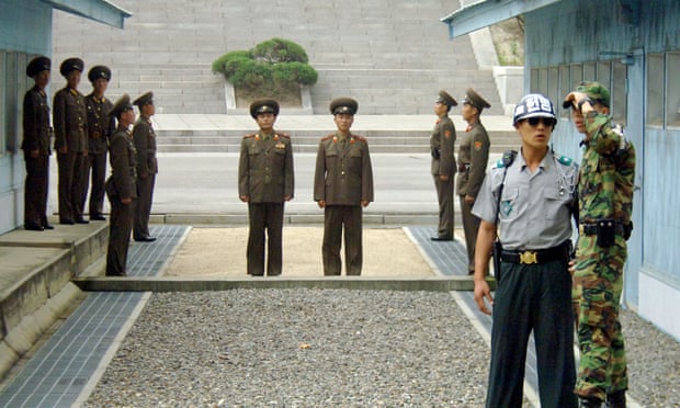 North Korean soldiers stand guard as South Korean soldiers chat in the DMZ. 