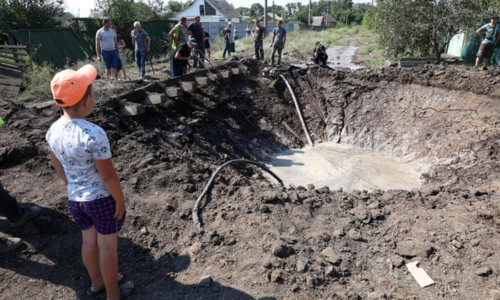 A boy looks on as communal service employees work around a crater created after a Russian missile strike in the town of Kostiantynivka, in the Donetsk region.