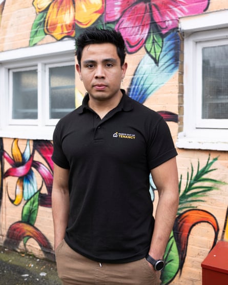 Jorge Gomez stands in front of a wall painted in a colourful floral mural