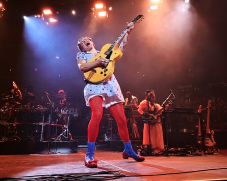 Playing a guitar on stage in a blue dress and red tights