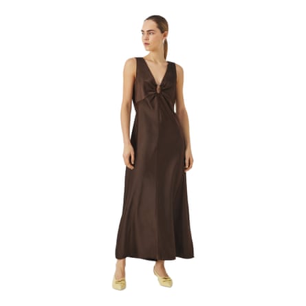 A model wears a bias cut v-neck sleeveless dress in dark chocolate brown. The model wears butter yellow shoes.