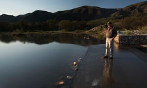 Farmer Pieter Kruger stands on a weir on his farm