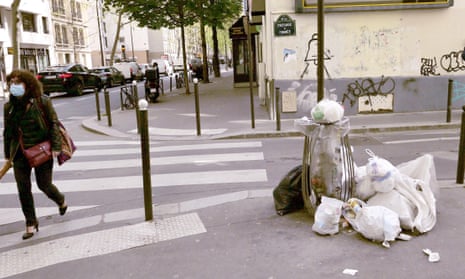 A woman walks past rubbish in a street in Paris