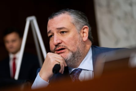 a man in a suit speaks while seated at a dais