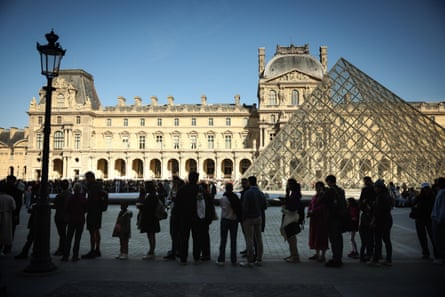 People queue to enter the Louvre on a sunny day