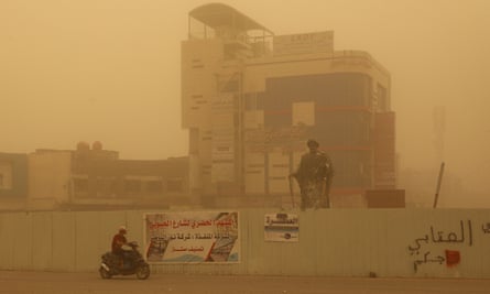 A man rides his scooter in a street during a dust storm in Nasiriyah.