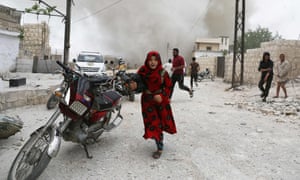 Syrians run for cover during an airstrike in Idlib on 30 May. 