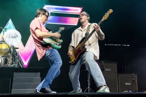 The two men face each other playing guitars
