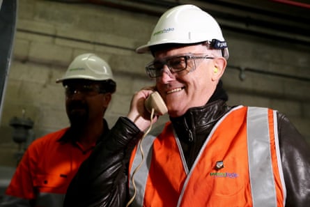 Malcolm Turnbull, wearing a hard hat and safety vest, smiles while speaking into a telephone at a power station