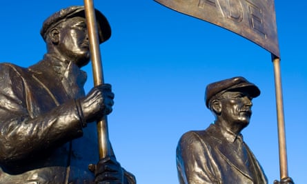 A lifesize bronze statue showing two men in flat caps holding a banner