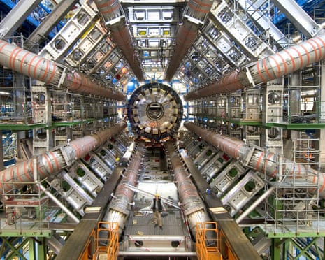 A man stands among the enormous star-shaped construction of metal tubes of the Large Hadron Collider Atlas detector
