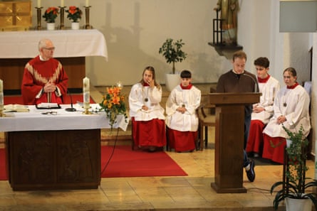 Marius Buhl speaks in a church with choir members sitting behind him