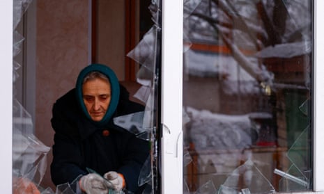 Local resident Nadiia Matviienko removes pieces of glass from a broken window of her house in Kyiv