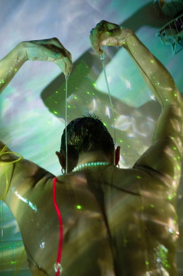 A figure drips an oily substance down their own back