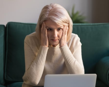 Stressed mature woman sitting on a sofa staring at a laptop