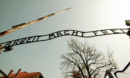 علامة Arbeit Macht Frei مظللة أمام السماء.