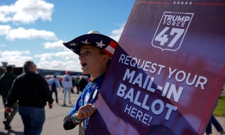 A person holds a sign asking people to request their mail-in ballot at a Trump rally in Mosinee, Wisconsin.