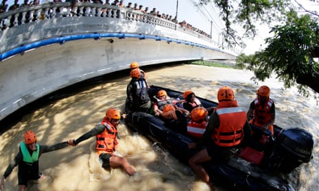 As bystanders look on from a bridge, Filipino soldiers rescue people caught in floodwaters in the town of Calumpit