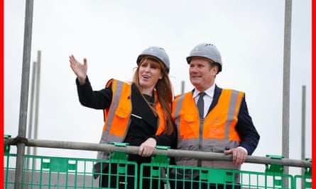 Angela Rayer and Keir Starmer, both with hard hats and high-vis jackets, stand on some scaffolding at a housing development in South Ribble in Lancashire
