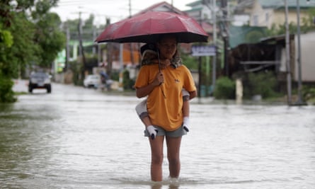 A woman carrying a child wades through floodwaters in the town of Paoay, Ilocos Norte, Philippines on Wednesday.