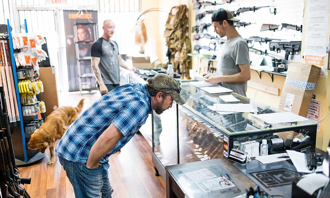 Customers look at guns in a store