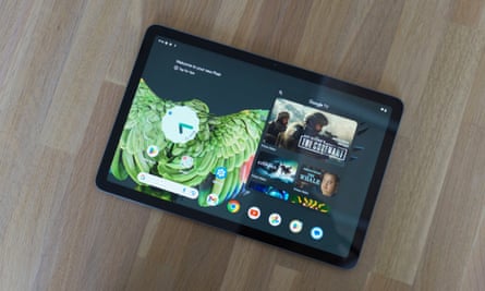 The Google Pixel Tablet showing the home screen laying on a table.