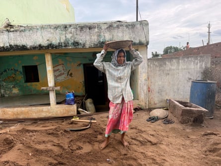 A woman holds a bowl above her head on a construction site