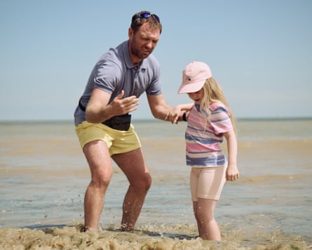 A man and a young girl are shown on the beach.