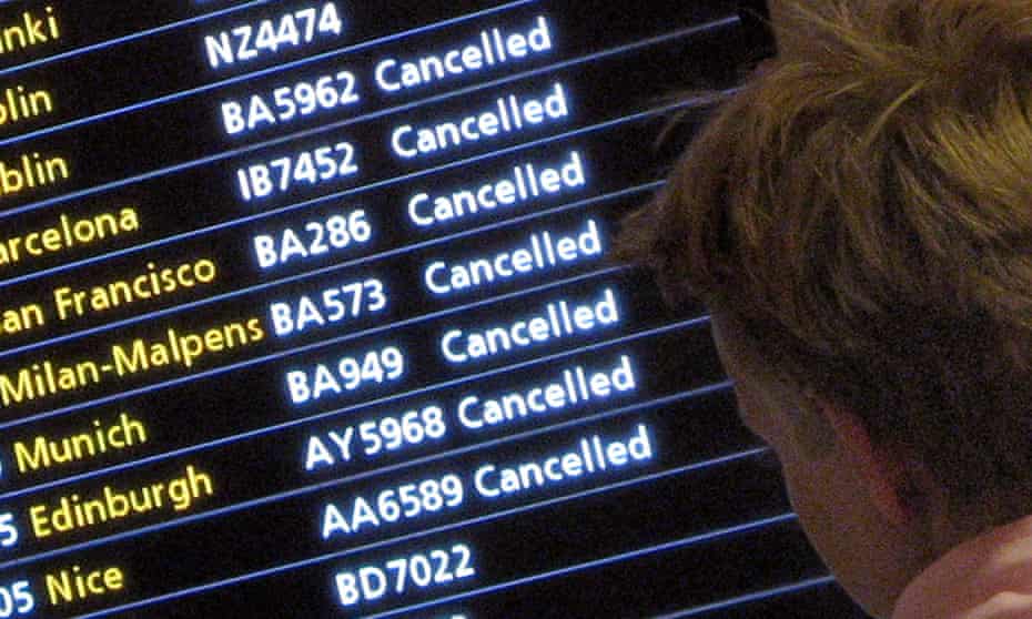 A passenger looks at a flight arrivals screen showing cancellations