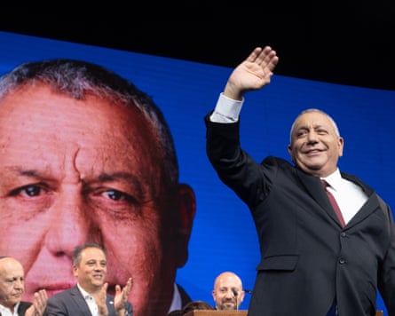 Gadi Eisenkot waves to supporters at an election night rally, his image shown on screen.