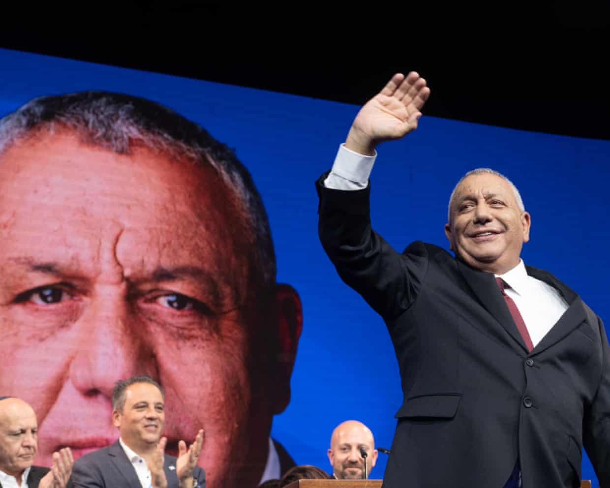 Gadi Eisenkot waves to supporters at an election night rally, his image shown on screen.