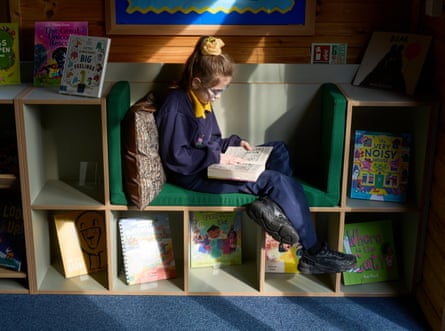 A girl sits reading on a small cushioned bench