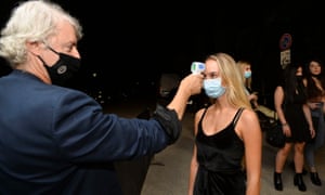 Workers check the body temperatures of customers at the entrance to the ‘Old Fashion’, a famous restaurant and nightclub in Milan, northern Italy, in July.