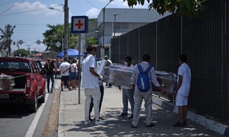 People wrap a coffin with plastic sheeting outside a hospital in Guayaquil, Ecuador