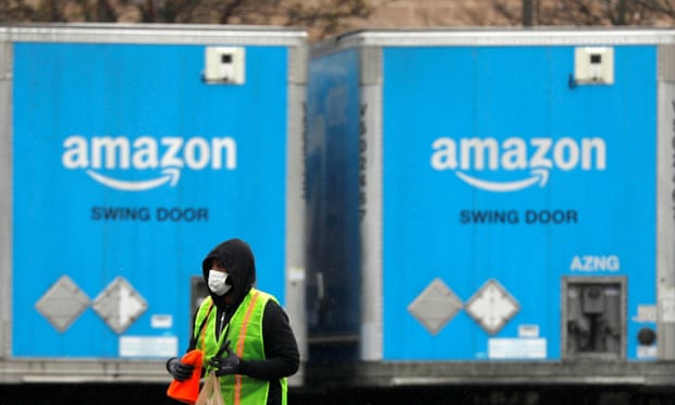 A worker in a face mask walks by trucks parked at an Amazon facility in Bethpage on Long Island, New York, on 17 March.