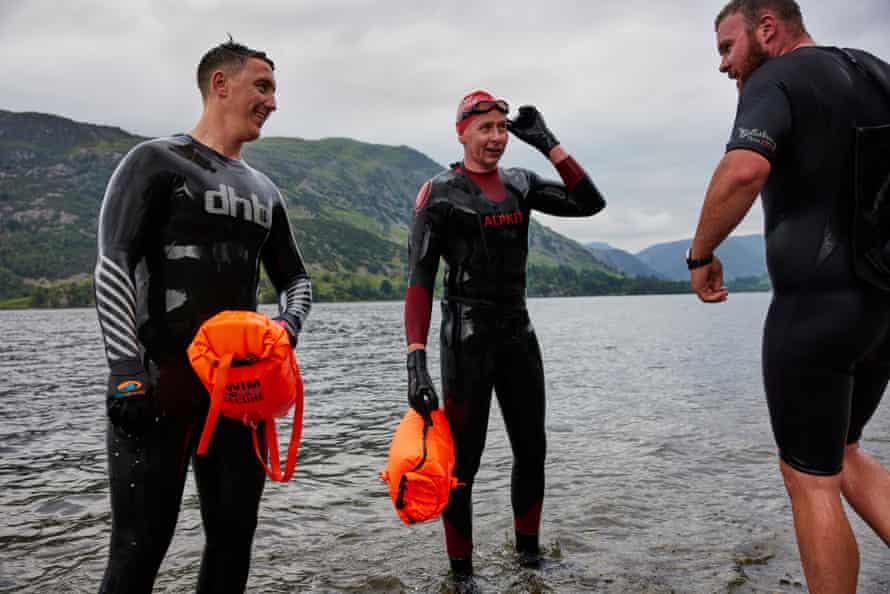 The three friends at the water's edge in wetsuits