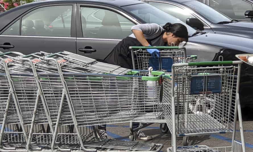 A worker sanitizes shopping carts at a Whole Foods in Los Angeles.