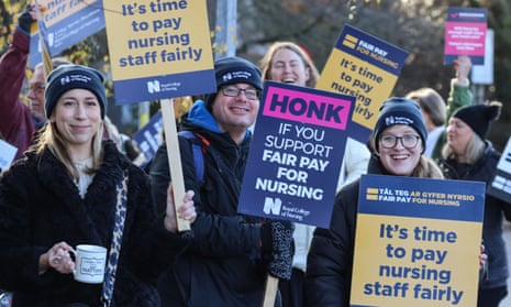 Nurses with placards and holding mugs of drink