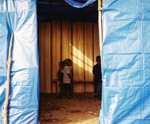 Children stand inside a tent