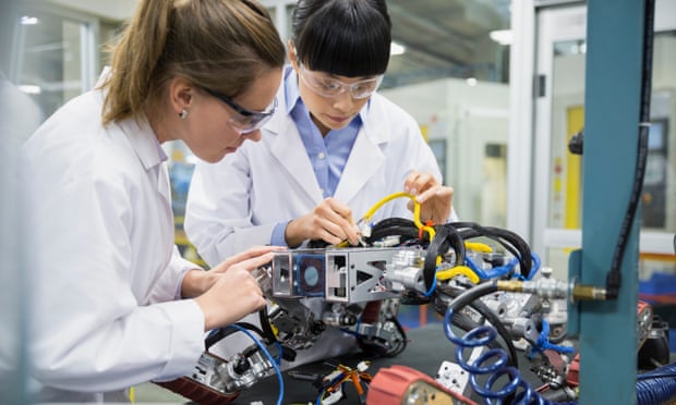 Female engineers assembling robotics in factory
