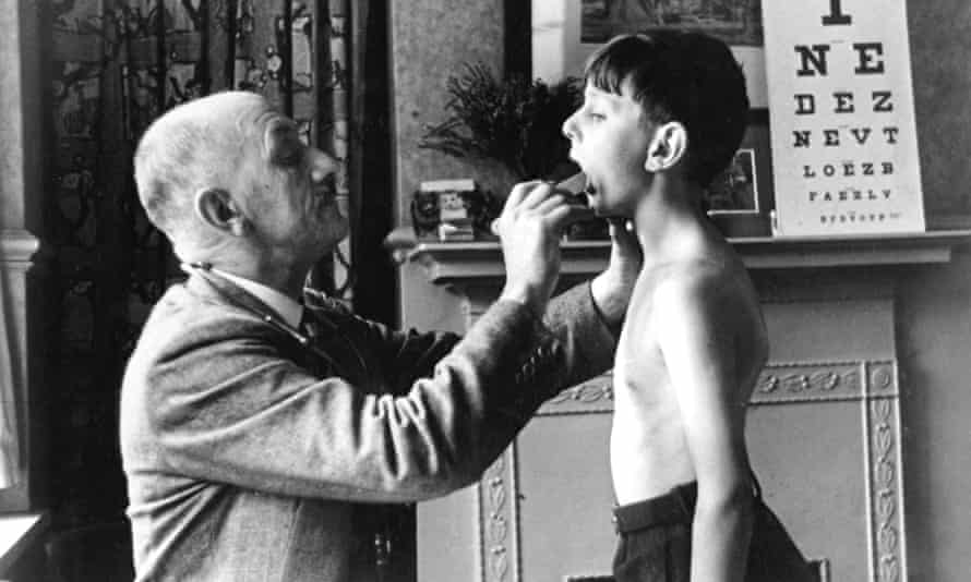 A doctor checks a young boy’s tonsils, December 1935.