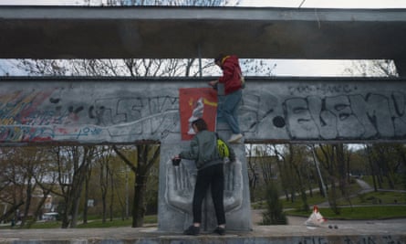 Two artists paint on a public structure outside